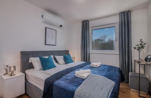 a bedroom with a bed with blue pillows and a window at Premium Apartments Mellea in Vantačići