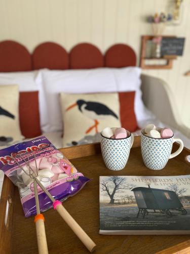 a table with two cups of eggs and a book at Ledmacoy Shepherds Huts in Strathdon