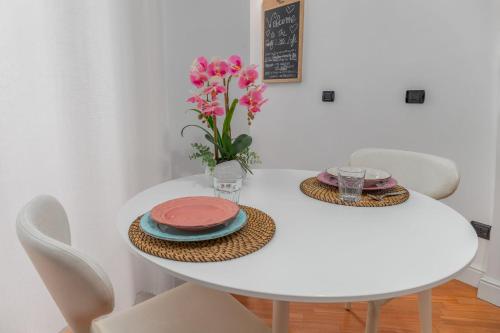 una mesa de comedor blanca con un jarrón de flores rosas en Pretty Little Loft en Rho