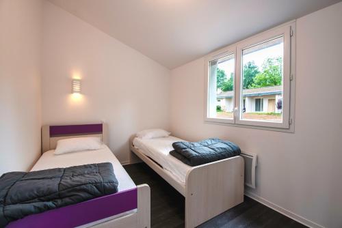 dwa łóżka w pokoju z oknem w obiekcie Aux Portes des Monts d'Aubrac w mieście Espalion