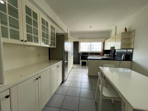 a kitchen with white cabinets and a white floor at Spacious Apartment by Platform 357 in Nicosia