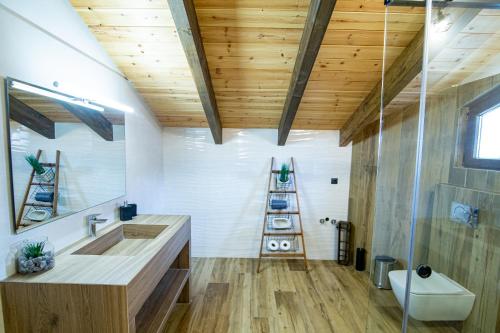Łazienka z dużą umywalką i drewnianym sufitem w obiekcie Ερυθρελάτη w Kalawricie