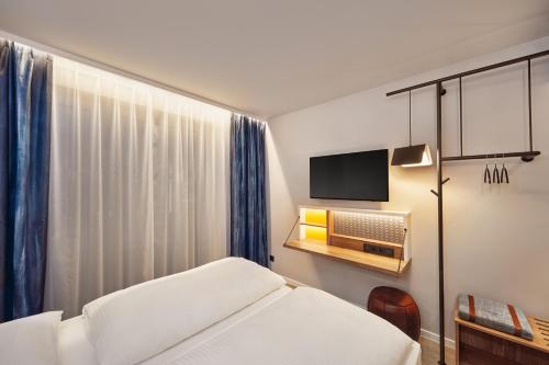 a hotel room with a bed and a television at H2 Hotel Mainz in Mainz