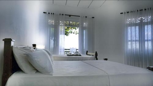 a white bedroom with a bed and a window at Ananthaya -the infinity in Kalutara