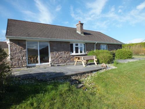 a stone house with a bench in front of it at Lark Rise Holiday Home Glenbeigh by Trident Holiday Homes in Glenbeigh