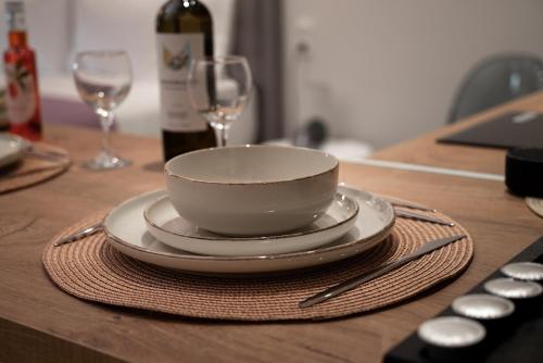 a bowl and plates on a table with wine glasses at KA Luxury Apartments in Mantoúkion