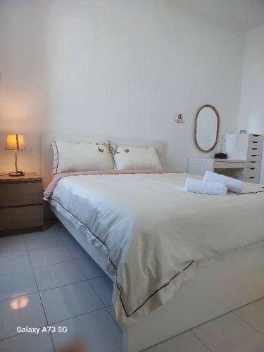 1 dormitorio con 1 cama blanca grande y espejo en Seaview Homestay Kt Pangsapuri Ladang Tanjung, en Kuala Terengganu