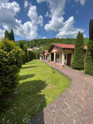 a walkway leading to a house with bushes and trees at Вили Тихия Кът in Ribarica