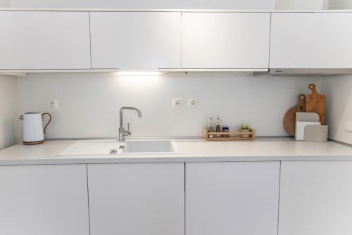 a kitchen with white cabinets and a sink at TheasHomly in Kastanéa