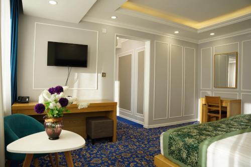 una habitación de hotel con una cama y un jarrón de flores en UB Grand Hotel en Ulán Bator