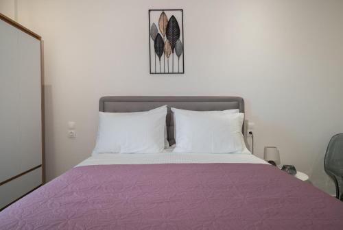 a bed with a purple blanket and white pillows at KA Luxury Apartments in Mantoúkion