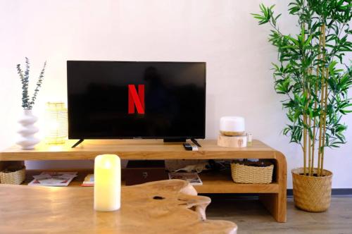 une télévision sur une table en bois avec la lettre n dessus dans l'établissement Maison « Ubud » love room spa, à Berre-lʼÉtang