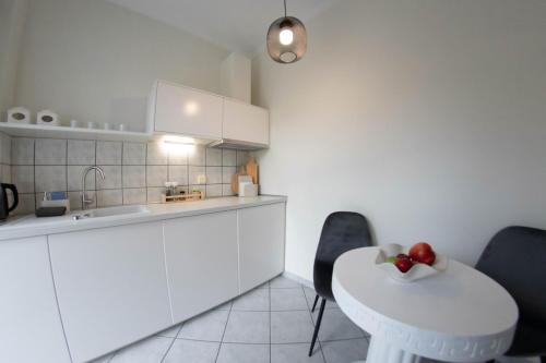 a kitchen with white cabinets and a white table and chairs at TheasHomly in Kastanéa
