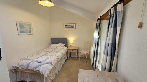 a small bedroom with a bed and a table at Place Lodge in Porthscatho