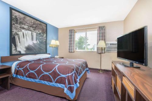 a hotel room with a bed and a flat screen tv at Super 8 by Wyndham Corbin KY in Corbin