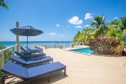 a patio with chairs and an umbrella and the ocean at Del Playa #1 Condo in West End