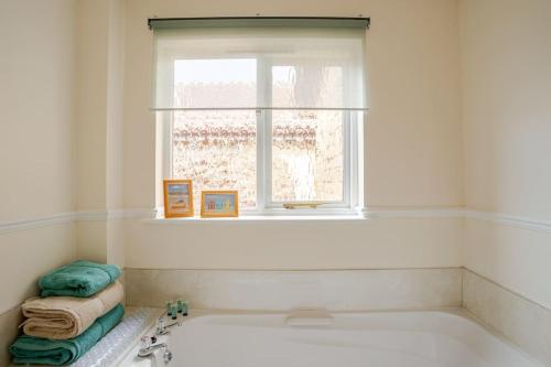 La salle de bains blanche est pourvue d'une baignoire et d'une fenêtre. dans l'établissement Tanglewood, à West Ashton