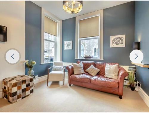 a living room with a brown leather couch and blue walls at Ferrymans Rest in Dartmouth