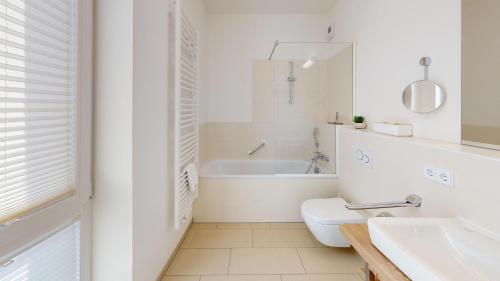 y baño blanco con aseo y bañera. en Südkap E-05, en Pelzerhaken