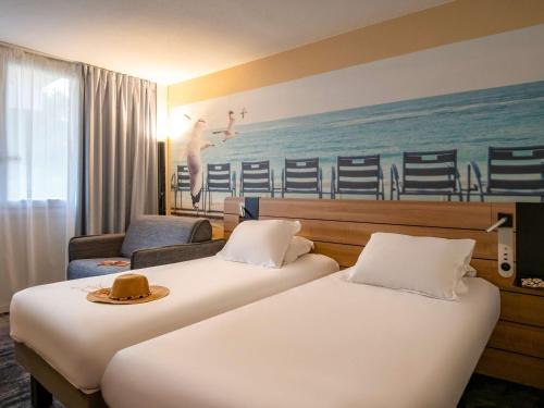 a hotel room with two beds with a hat on top at Novotel Antibes Sophia Antipolis in Valbonne