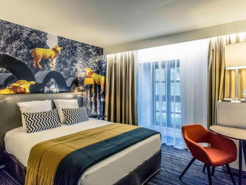ブールジュにあるホテル ドゥ ブルボン グラン ホテル メルキュール ブルージュのベッド、椅子、デスクが備わる客室です。