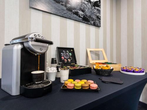 a table with a coffee maker and some pastries at Hotel De Bourbon Grand Hotel Mercure Bourges in Bourges