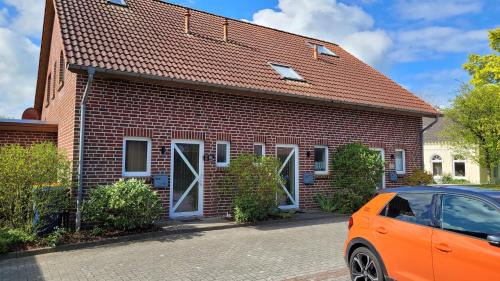 an orange car parked in front of a brick house at Ferienhaus Kleine Möwe in Altfunnixsiel