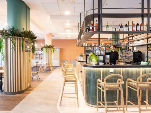 a bar in a restaurant with a man behind the counter at ibis Marseille Centre Euromed in Marseille