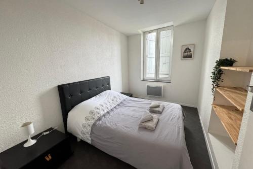 a bedroom with a bed with a black headboard and a window at Côté jardin appartement centre Gramat in Gramat