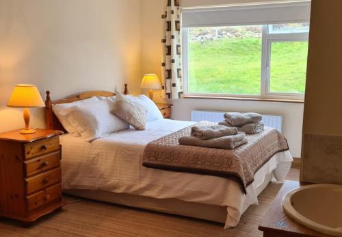a bedroom with a bed with two towels on it at Mourneen Cottage, Cleggan in Cleggan