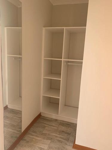an empty closet with white shelves in a room at Grandview adventure and guesthouse in East London