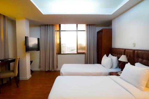 Habitación de hotel con 2 camas y TV en Hotel KBA, en Yangón