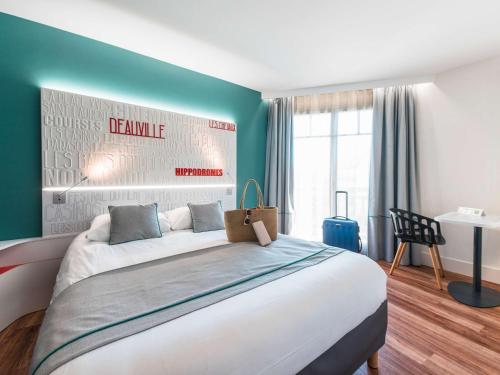 a bedroom with a large bed and a desk at ibis Styles Deauville Centre in Deauville