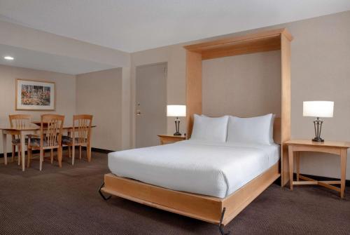 1 dormitorio con 1 cama, mesa y sillas en Ramada Plaza by Wyndham Calgary Downtown, en Calgary