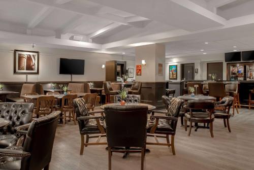 a restaurant with tables and chairs and a flat screen tv at Ramada Plaza by Wyndham Calgary Downtown in Calgary