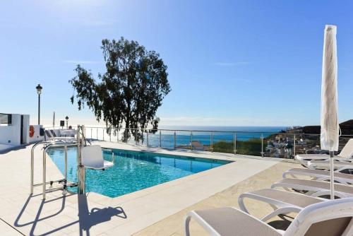 a swimming pool with chairs and the ocean in the background at Casa Grace in Nerja