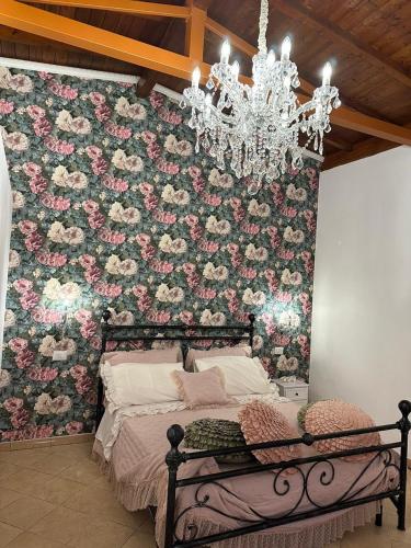 a bedroom with a floral wall with a bed and a chandelier at Il Rifugio 1711 in Borgo Vodice