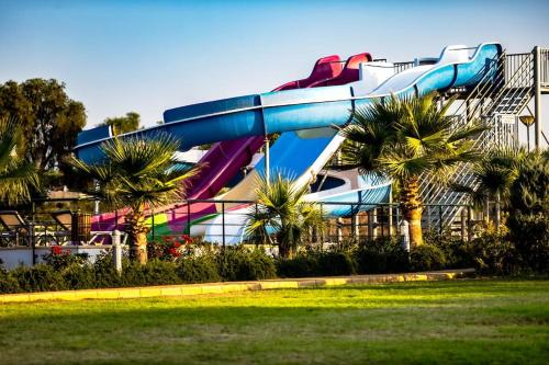 a roller coaster in a park with palm trees at Thalassa Beach Resort 2 Bedroom Penthouse with a Hot Tub in Vokolidha