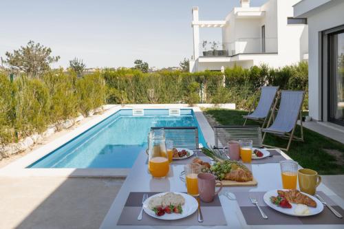 uma mesa com comida e bebidas junto a uma piscina em Pérola Lux Villa no Vau