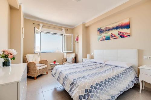 een slaapkamer met een bed, een stoel en een raam bij Morasol 6-4 in Nerja