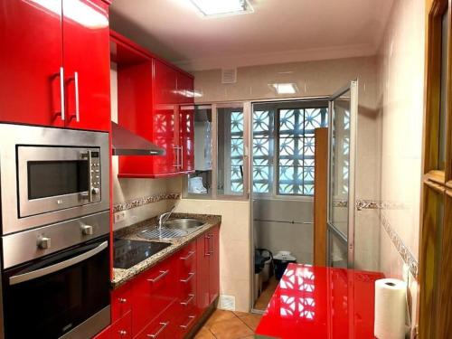 eine rote Küche mit einer Spüle und einer Mikrowelle in der Unterkunft Gransol con piscina 600m playa in Rincón de la Victoria