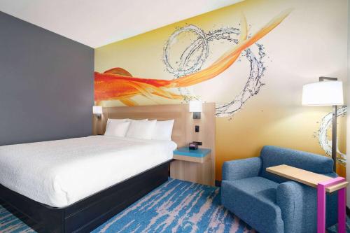 a bedroom with a bed and a blue chair at La Quinta Inn & Suites by Wyndham San Antonio Seaworld LAFB in San Antonio