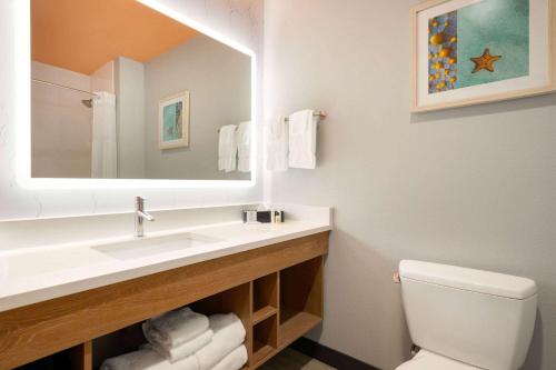 a bathroom with a sink and a toilet and a mirror at La Quinta Inn & Suites by Wyndham San Antonio Seaworld LAFB in San Antonio