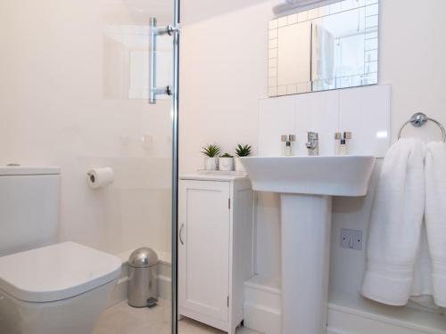 Baño blanco con lavabo y aseo en Studio Apartment ideal for short or long stays, en Pershore