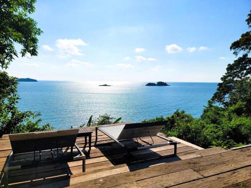 stół piknikowy i ławka na tarasie z widokiem na ocean w obiekcie Koh Chang Cliff Beach Resort w mieście Ko Chang