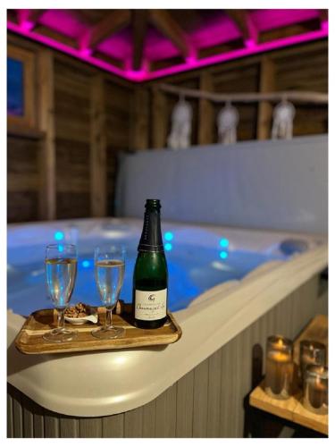 - une bouteille de vin et deux verres sur un plateau à côté d'une baignoire dans l'établissement Les Ricochets - Maison d'hôtes, à Saint-Denis-lès-Martel
