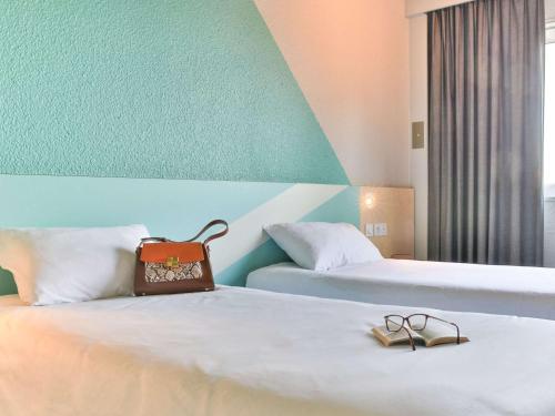 a hotel room with two beds with shoes on them at ibis budget Tours Sud in Chambray-lès-Tours