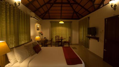 1 dormitorio con 1 cama y 1 mesa con sillas en Palmgrove Lake Resort en Alleppey