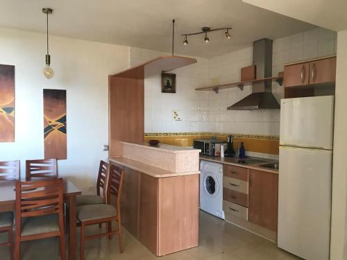 eine Küche mit einem weißen Kühlschrank sowie einem Tisch und Stühlen in der Unterkunft Espectacular residencial en 1a linea con piscina in Benajarafe