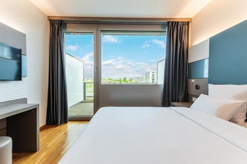 a hotel room with a large bed and a large window at B&B HOTEL Lausanne Crissier in Lausanne